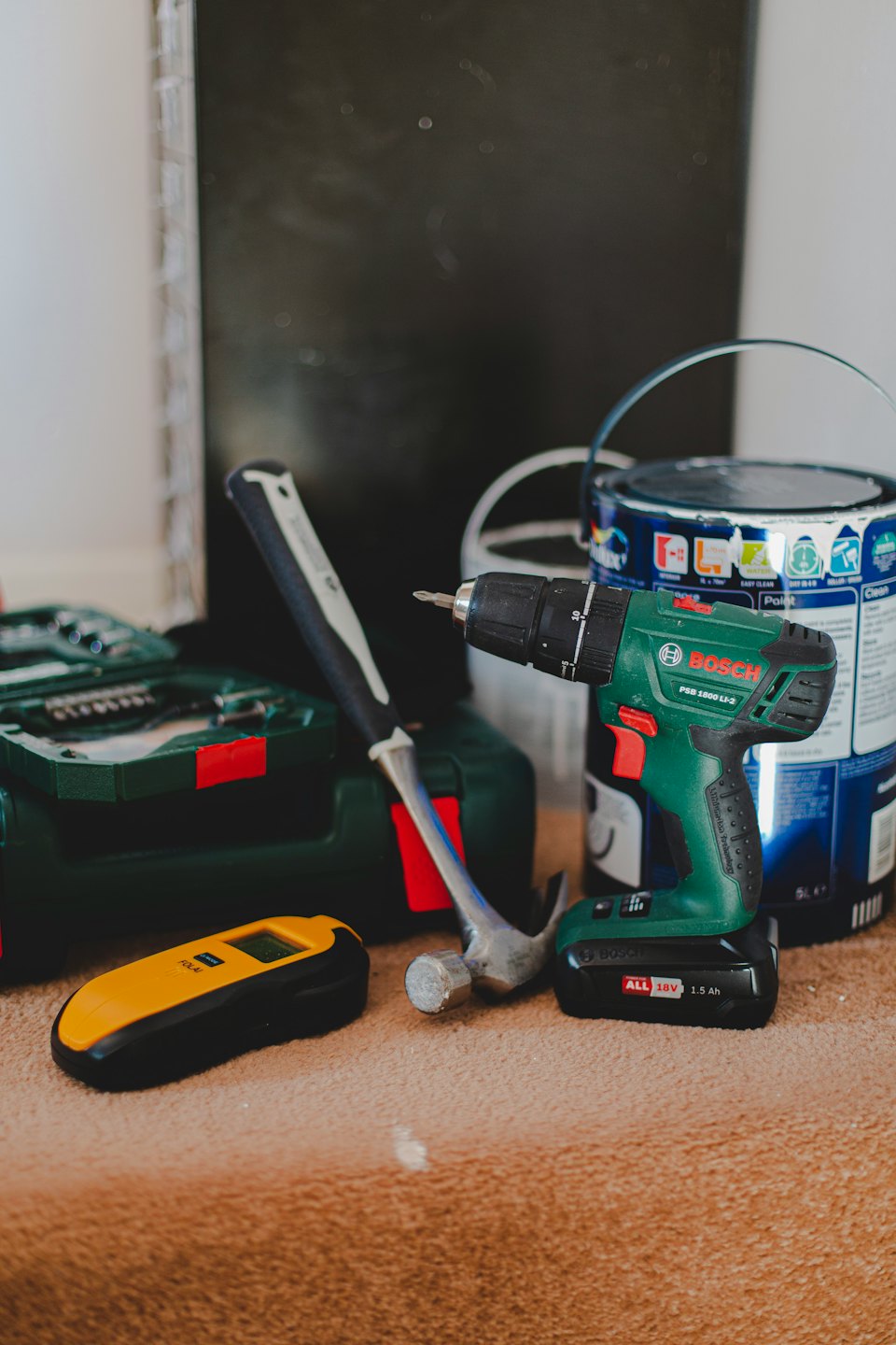Green drill, hammer, and scanner on carpet.