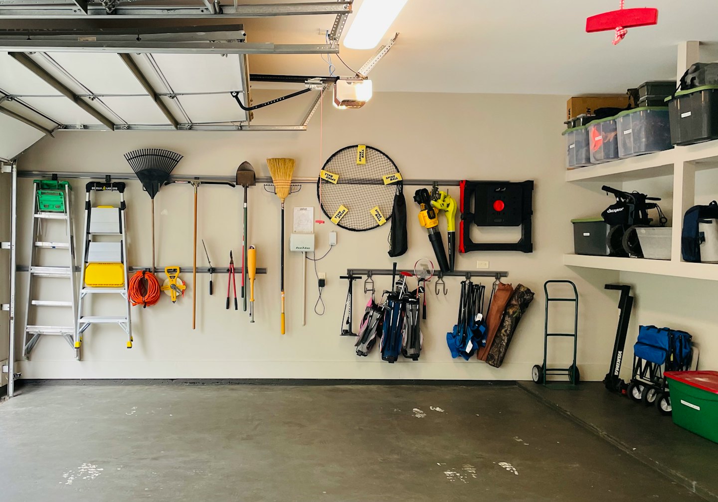 Organized garage wall racks hold gardening tools and hardware.
